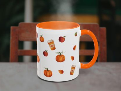 Orange-accented mug with autumn-themed designs, featuring pumpkins, apples, leaves, and coffee cups. Steam rises, suggesting a warm drink inside. Cozy vibe.