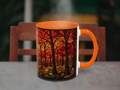 Orange mug with a vibrant autumn forest design, featuring red and orange leaves on dark trees. It sits on a table, exuding warmth and coziness.