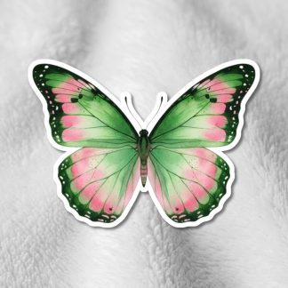 A vibrant butterfly with green and pink wings rests on a soft, textured gray surface. The butterfly's symmetrical design adds a sense of calm and beauty.