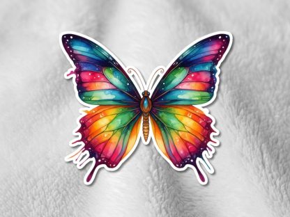A vibrant rainbow butterfly sticker with melted edges on a soft, textured white background. The butterfly is symmetrical and multicolored, conveying a sense of whimsy and creativity.