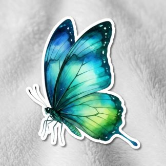 A vibrant, blue and green butterfly sticker with detailed wings is placed on a soft, white textured fabric, creating a serene and delicate contrast.