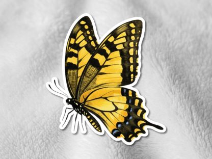 A vibrant yellow and black butterfly, resembling a swallowtail, is seen resting on a light, textured background. The image conveys a sense of elegance.
