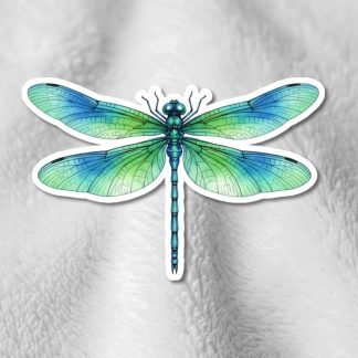 A vibrant dragonfly sticker with intricate green and blue wings is set against a soft, light gray textured fabric background, conveying a serene and natural tone.