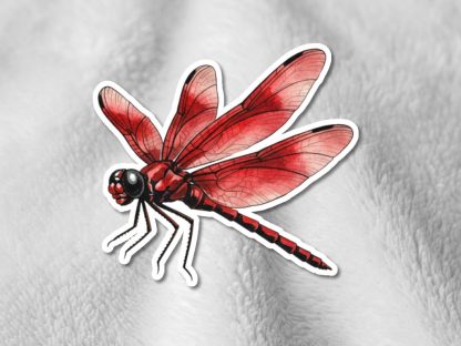 Illustration of a vibrant red dragonfly sticker on a soft, white textured background. The wings are detailed, creating a lively and artistic feel.