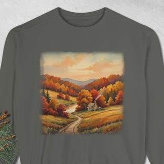 A gray sweatshirt features a serene autumn landscape, with a winding path leading to a small cabin surrounded by vibrant fall trees and rolling hills under a soft, warm sky.