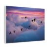 A large canvas wall art piece depicts a flock of birds flying over colorful, fluffy clouds at sunset. The vibrant sky contrasts with a gray couch below.