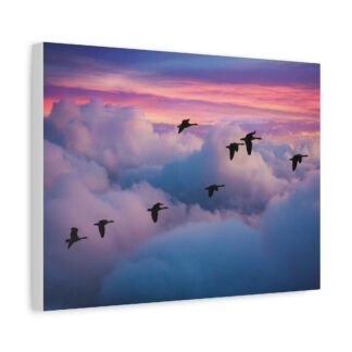 A large canvas wall art piece depicts a flock of birds flying over colorful, fluffy clouds at sunset. The vibrant sky contrasts with a gray couch below.