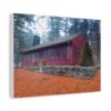 Canvas wall art print of a red cabin with numerous windows and a chimney stands amidst a forest. A decorated Christmas tree is on the right, with vibrant poinsettias below front windows.