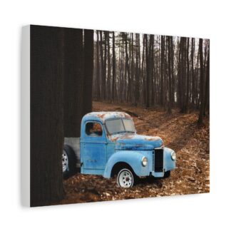 A rustic blue vintage truck with visible rust sits partially hidden among trees in a serene, sunlit forest. The earthy tones convey a nostalgic mood printed on canvas wall art.