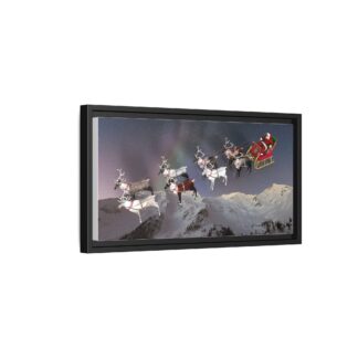A framed canvas artwork shows Santa in a red sleigh flying over snowy mountains, pulled by reindeer under a starry night sky. A plant and couch are visible below.
