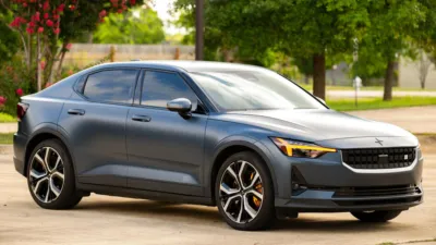 Photo of a Polestar 2 in dark blue with a matte-effect wrap (I think). The brake calipers are gold, indicating that it has the performance pack.