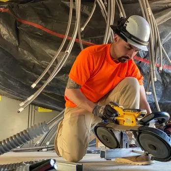 A skilled electrician from Sonoma Coast Electric, Inc is performing electrical installation work in a residential setting, featuring wires and tools neatly arranged.