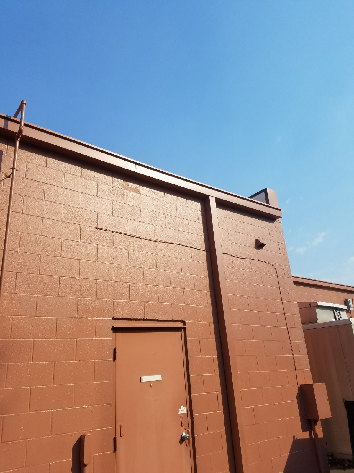 Freshly painted exterior block wall and service door on a commercial building after professional repainting.