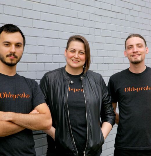 Three awesome people standing in front of a gray building.