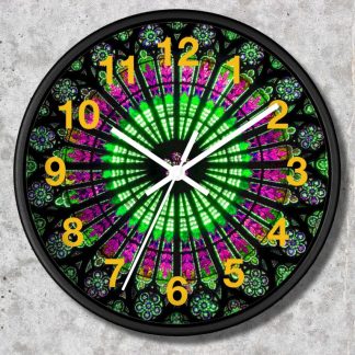 A colorful clock in a gothic style features a vibrant stained glass pattern with green and pink hues. Yellow numbers contrast against the dark frame, evoking a dynamic and artistic feel.