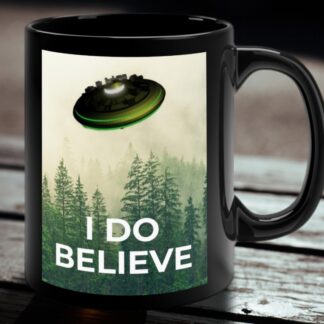 Black mug with a serene forest scene and a UFO hovering above. The words "I DO BELIEVE" are printed at the bottom, conveying a mysterious, whimsical tone.