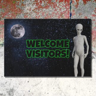 Outdoor welcome mat depicts an alien figure against a starry background with a full moon. Bold green text reads "Welcome Visitors!" against a cracked cement floor. Playful and inviting tone.