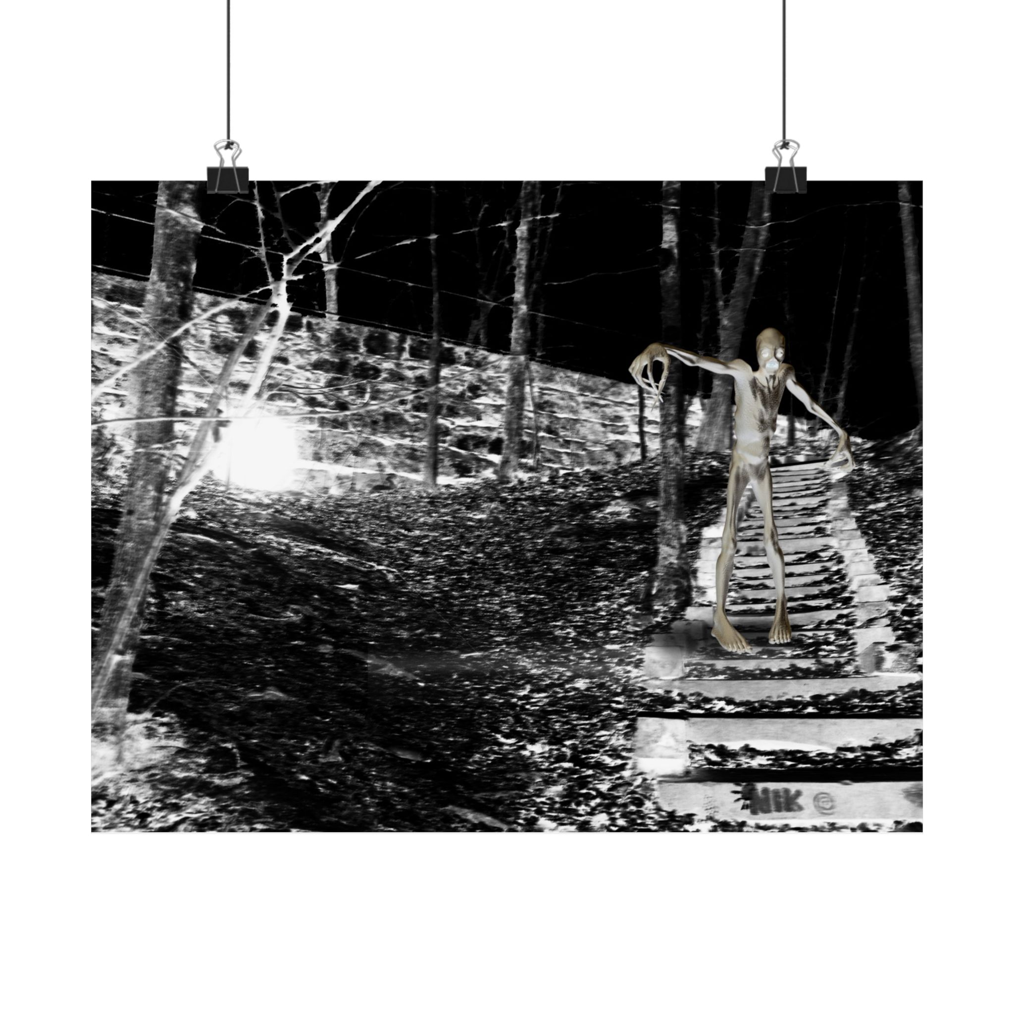 A black-and-white photo poster print on a brick wall, flanked by lanterns, shows a mysterious humanoid figure on forest steps at night, creating an eerie atmosphere.