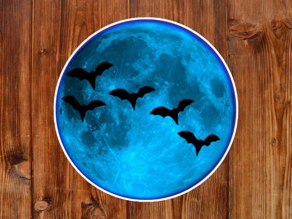Gothic sticker features bright blue moon with five silhouetted bats flying across it, set against a warm wooden background, creating a spooky and mysterious atmosphere.