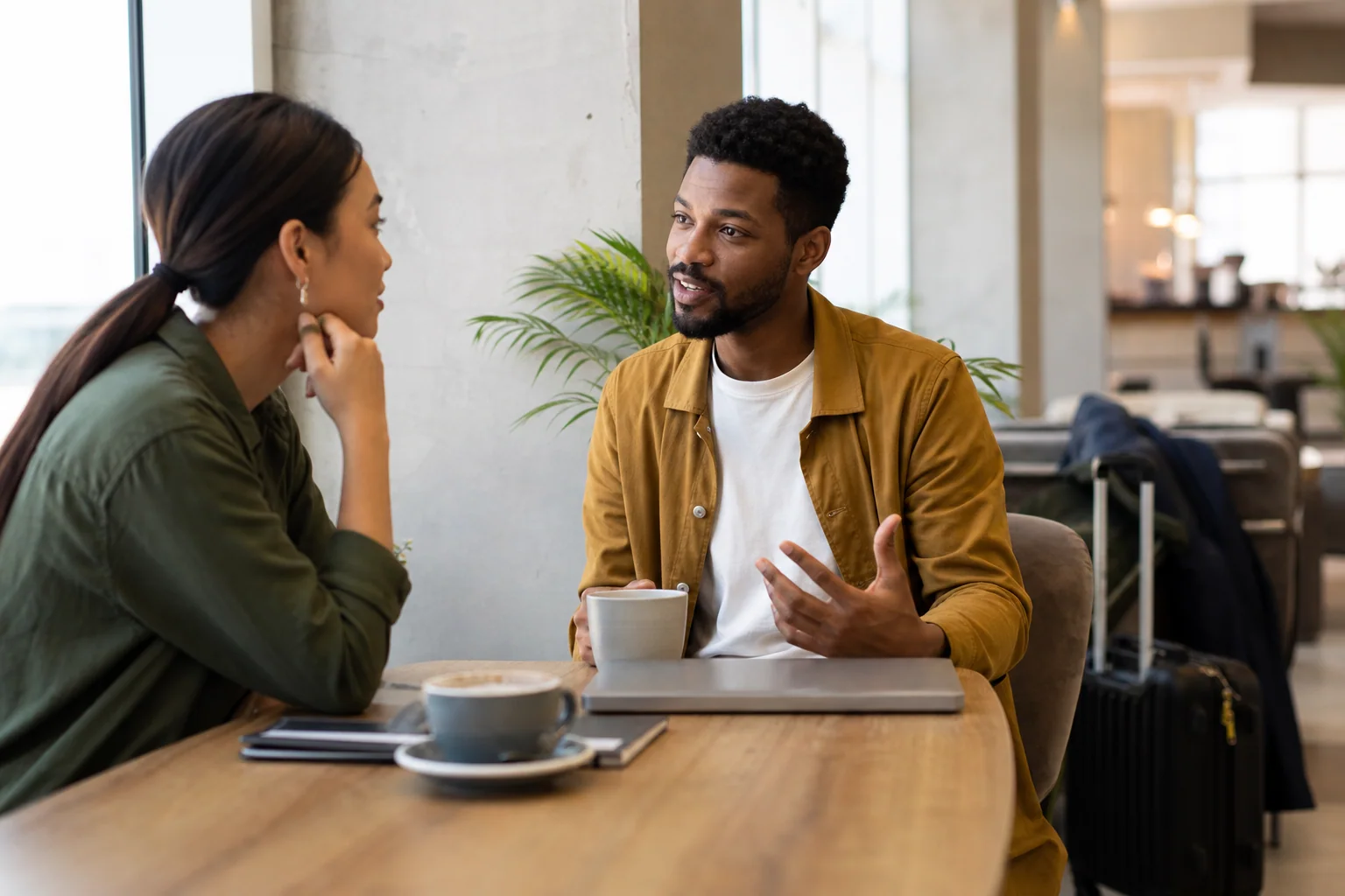 Duas pessoas conversam de forma descontraída em um ambiente contemporâneo entre cafeteria e coworking, sugerindo small talk natural em inglês.