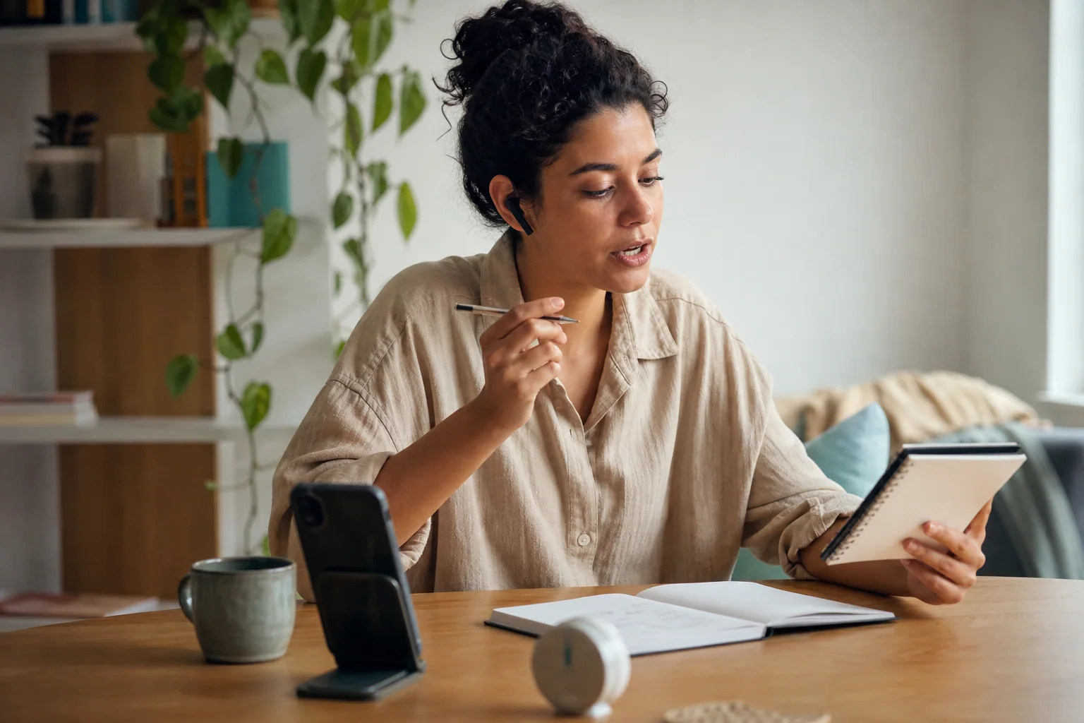 Pessoa estudando inglês por 15 minutos em casa com celular, fones, caderno e fala guiada em uma rotina curta e realista.