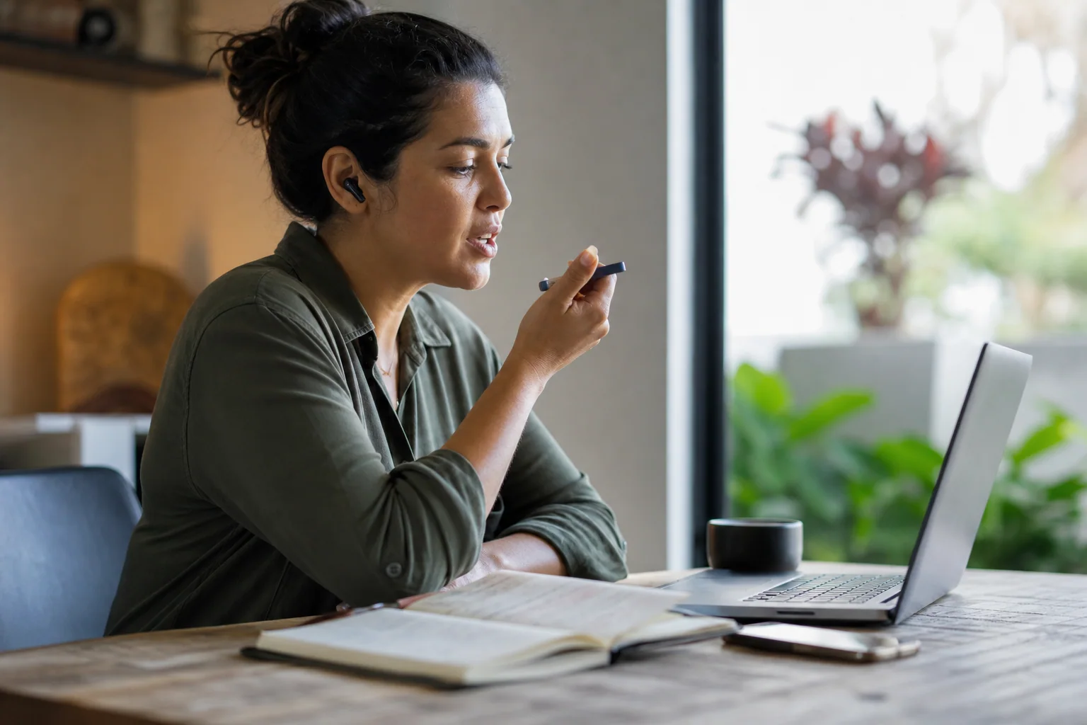 Pessoa brasileira praticando pronúncia em inglês com fones e caderno em um ambiente de estudo tranquilo.