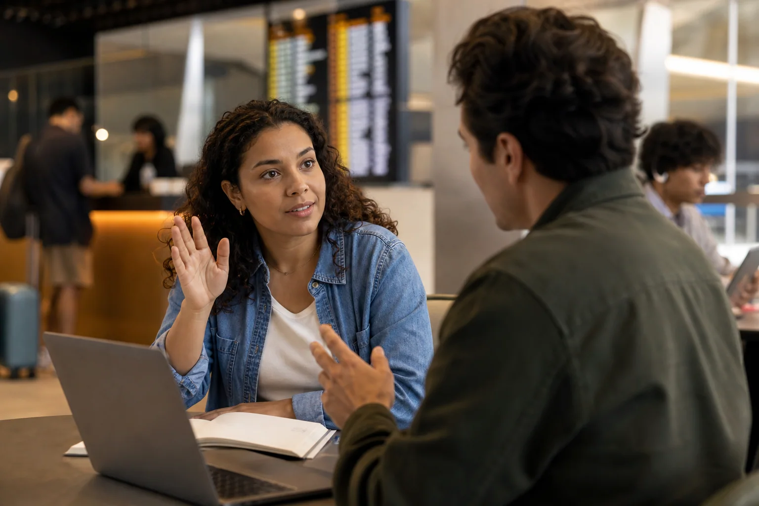 Pessoa adulta pede esclarecimento com educação durante uma conversa em inglês, em um ambiente que sugere atendimento, estudo e trabalho.