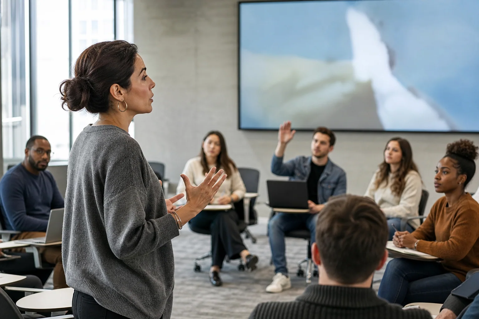 Professor conduzindo aula universitária em inglês com alunos adultos atentos em sala moderna.