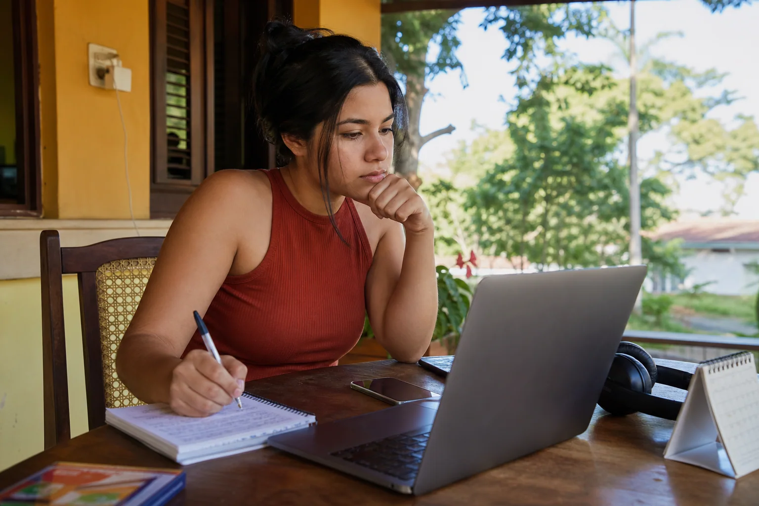 Pessoa em Roraima avalia no notebook uma oportunidade de curso gratuito de inglês com anotações e rotina de estudo à mesa.