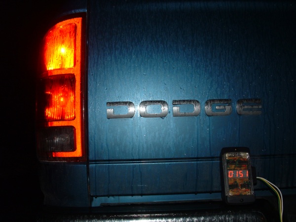 Rear end of a Dodge Ram pickup truck, with the turn signal lit, and a four-digit counter sitting on the bumper
