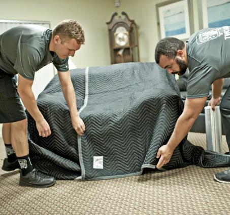 two men and a truck movers wrapping furniture for protection
