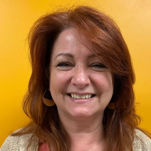 Bonni standing in front of a yellow wall smiling