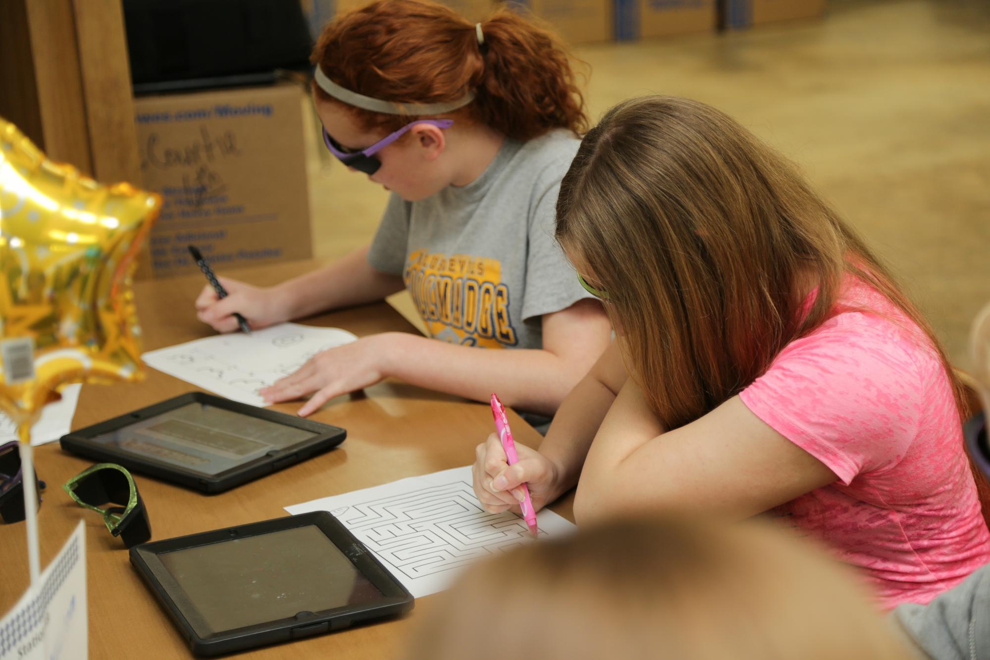 2 teens working on mazes at a table
