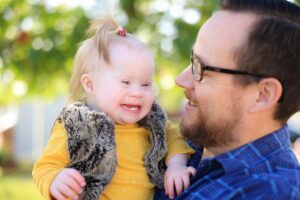 Close up of baby girl with ponytail smiling with her dad