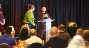 Man presenting at podium with woman standing to his right