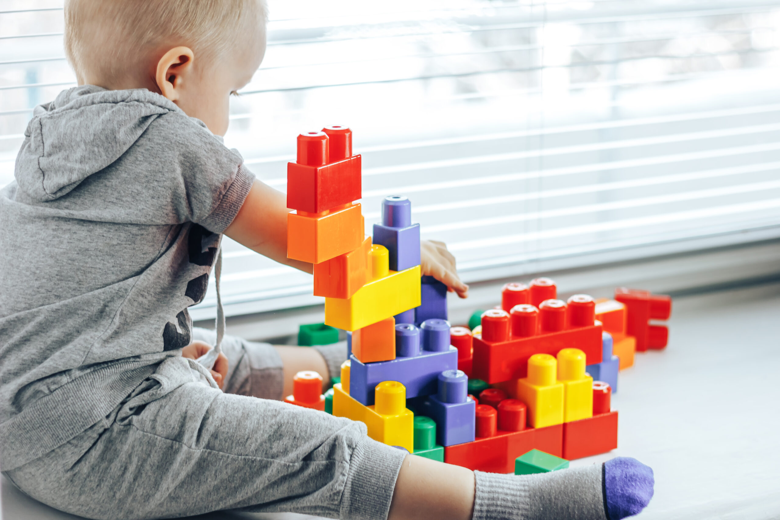 baby playing with colorful, stackable, plastic blocks