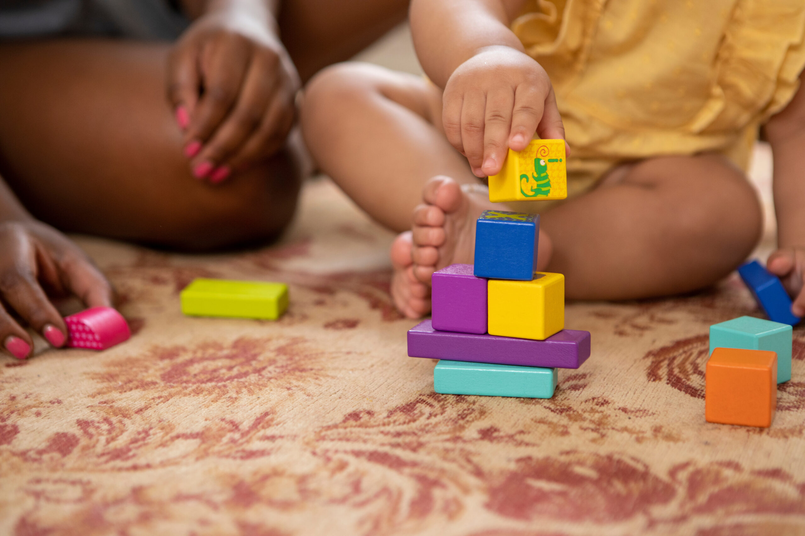 closeup of mother and baby stacking wooden blocks