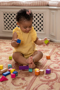 Baby girl (12-17 months) playing on floor with colorful blocks