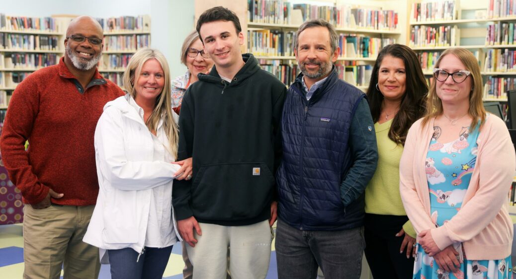 Smiling young man standing with his support team of Summit DD staff and providers around him