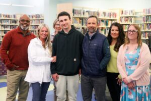 Smiling young man standing with his support team of Summit DD staff and providers around him