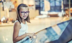 Smiling young girl studying map in shopping mall.
