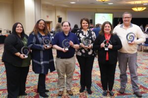 6 Summit DD staff members standing together, holding their 2023 Core Value Awards. Core Value Award Winners Deb Bailey, Rhonda Mallard, Paul Jankura, Melissa Skiljan, Julie Foster, and Todd Weaver at the 2024 Employee Recognition Breakfast.