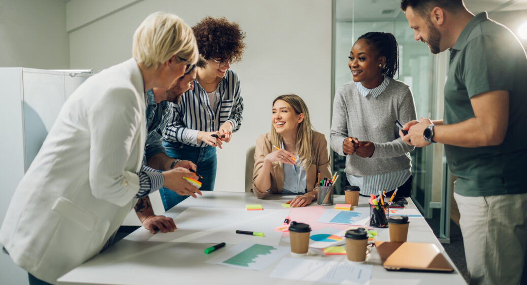 Multiracial business team on a meeting in a modern bright office Happy multiracial business team working together at corporate briefing gathered at table in the office. Smiling diverse colleagues in a boardroom discussing financial statistics together.