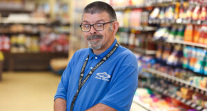 Portrait of an Acme employee, Scott, standing in front of the cheese isle.