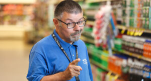 Portrait of an Acme employee, Scott, standing in front of the soda isle.