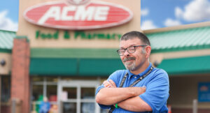 Portrait of an Acme employee, Scott, standing in from our the Acme entrance sign.