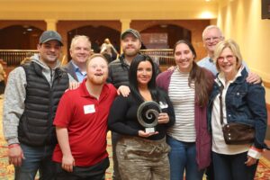 2024 Appreciation Award winner Britt Ferrara holding award surrounded by friends and family