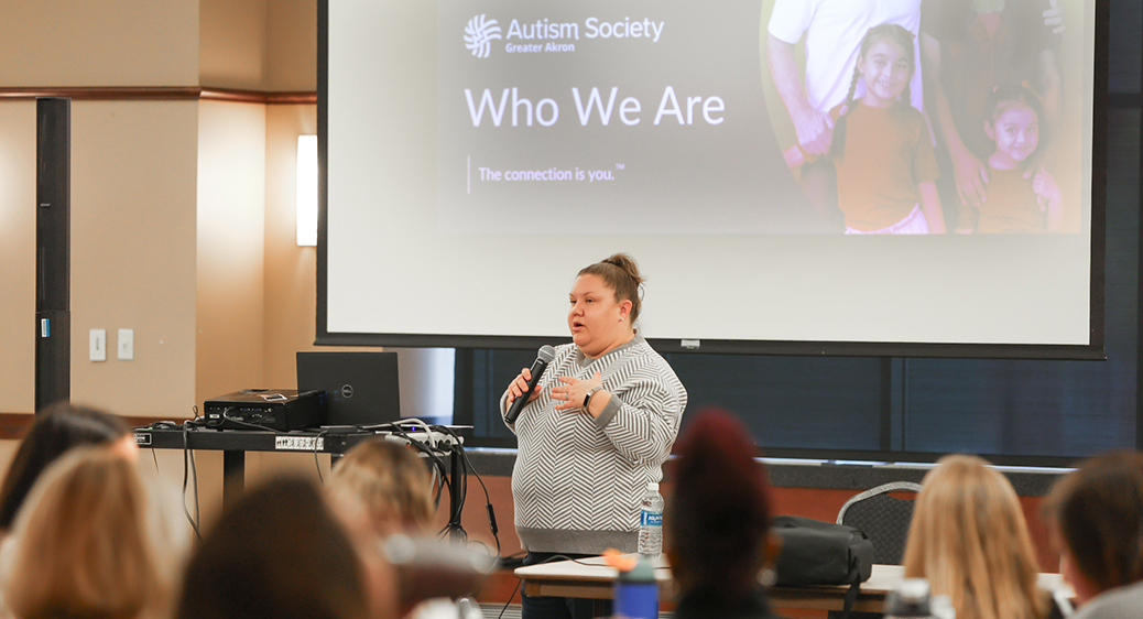 Image of a presenter in front of a crowd at the Summit DD EI Autism event.