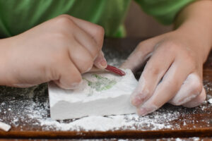 Child's hand is playing with the archaeological set. Child digging a dinosaur.