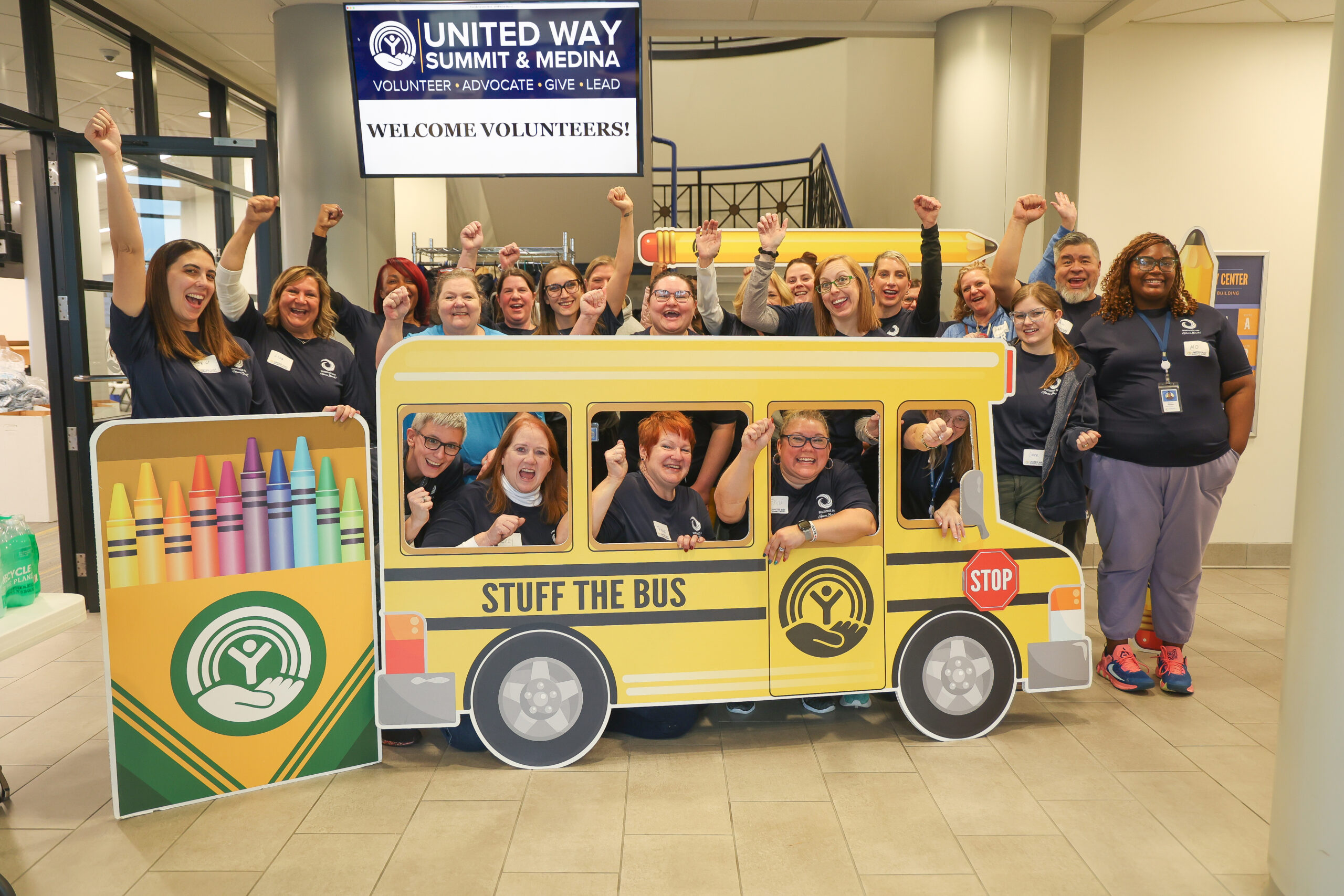 Group of staff members happily posing with carboard school bus.
